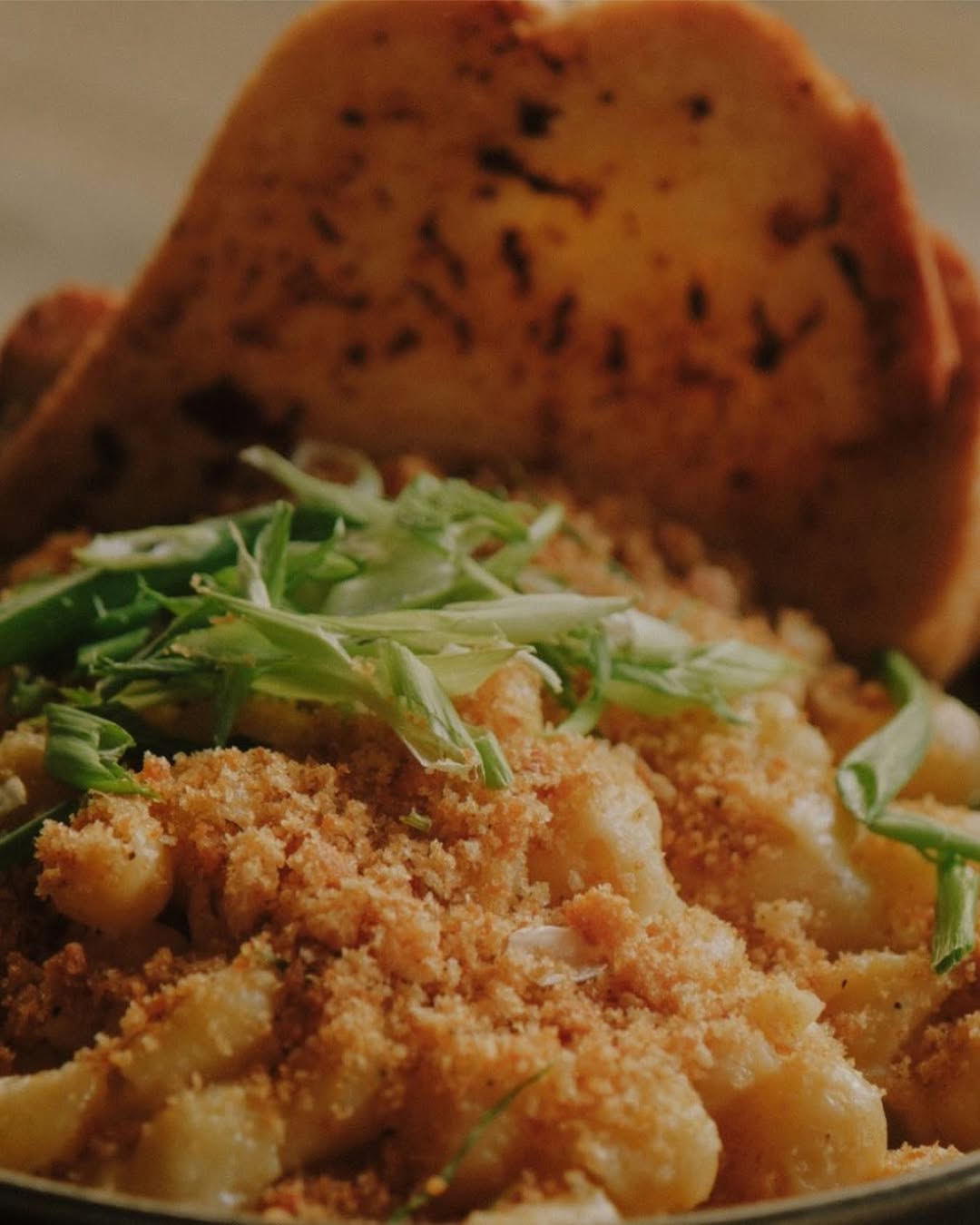 Our mac n cheese with aged white cheddar, asiago, curds, cracked black pepper and scallions. Served with sourdough garli